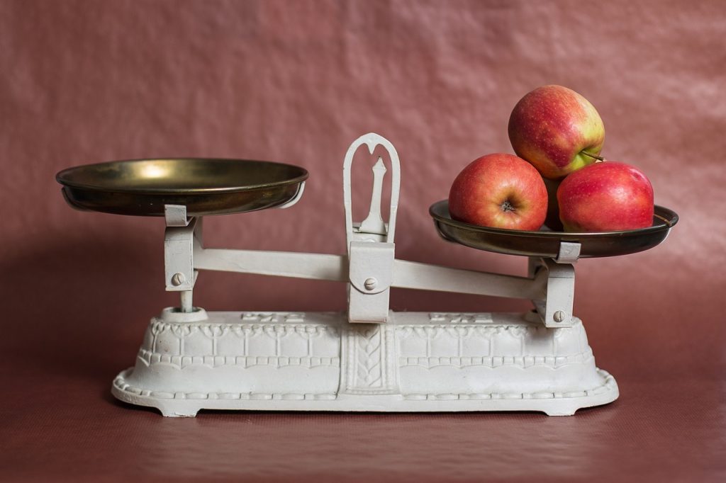 Une balance de cuisine avec trois pommes sur un côté.